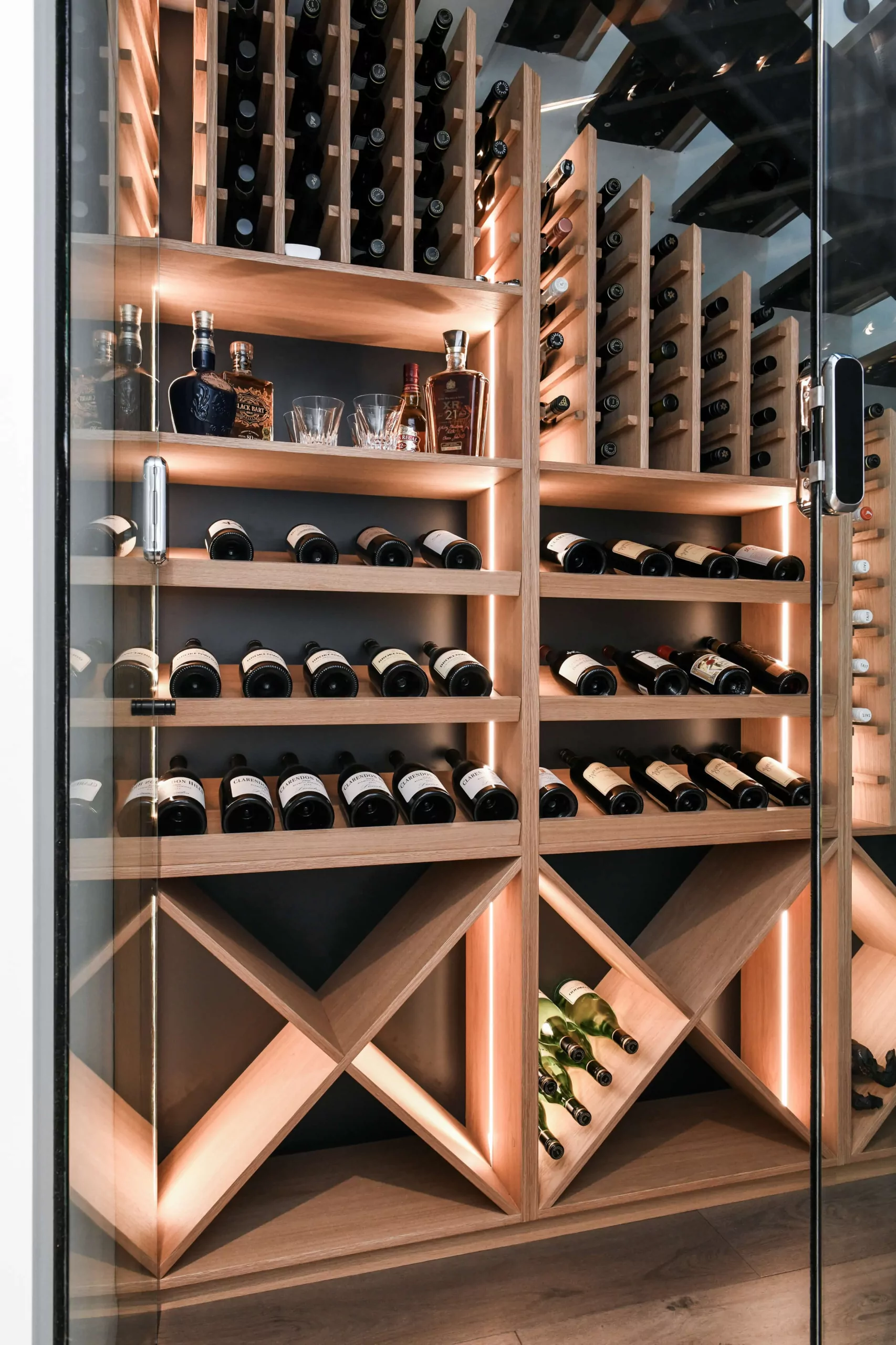 Climate-controlled under-stair wine cellar with glass walls and illuminated timber storage | Custom joinery by Improva, Mona Vale