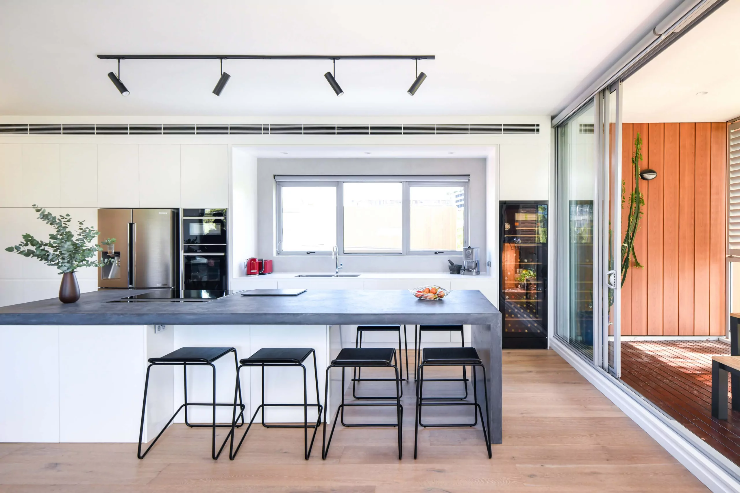 Concrete benchtop island with black metal bar stools | Custom joinery by Improva, Zetland