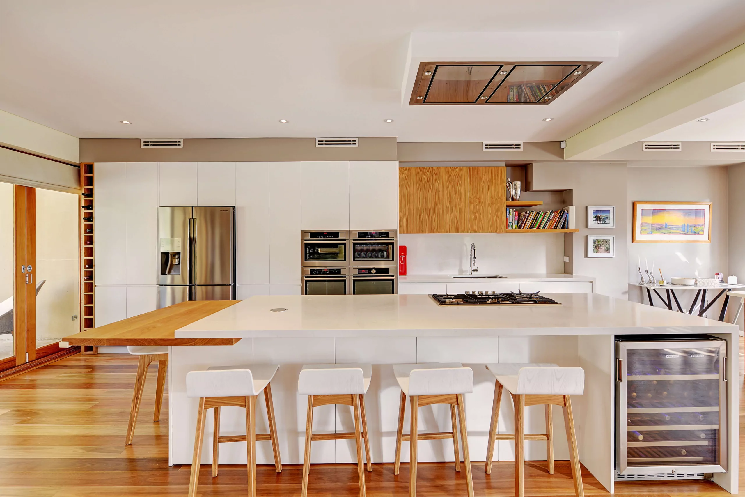 White stone and timber kitchen island with integrated cooktop and wine fridge | Custom joinery by Improva, Clontarf